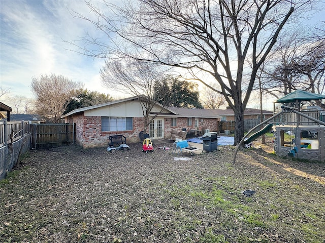 rear view of house featuring a playground and a patio