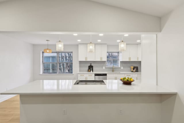 kitchen with black electric stovetop, decorative backsplash, sink, hanging light fixtures, and stainless steel dishwasher