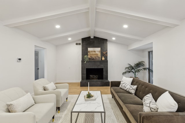 living room with light wood-type flooring, vaulted ceiling with beams, and a tile fireplace