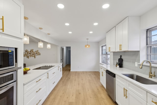 kitchen featuring appliances with stainless steel finishes, white cabinetry, decorative backsplash, sink, and pendant lighting