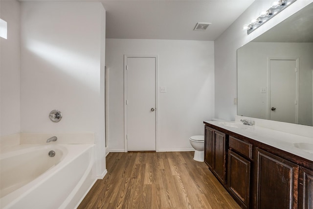 bathroom featuring hardwood / wood-style floors, toilet, vanity, and a bath