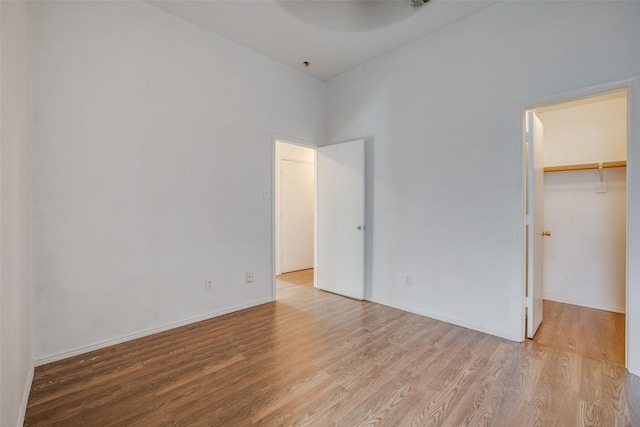 unfurnished bedroom featuring a closet, light hardwood / wood-style flooring, and a spacious closet