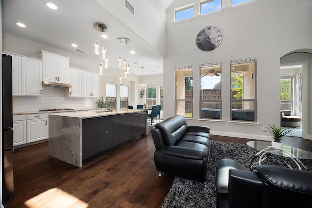 kitchen featuring an island with sink, visible vents, white cabinetry, and hanging light fixtures