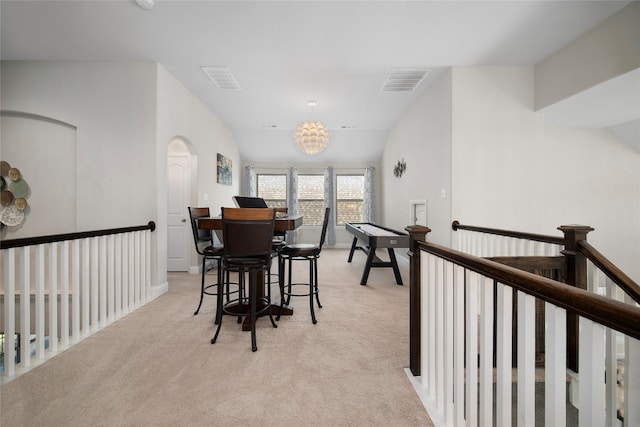 dining area with light colored carpet, vaulted ceiling, visible vents, and an inviting chandelier