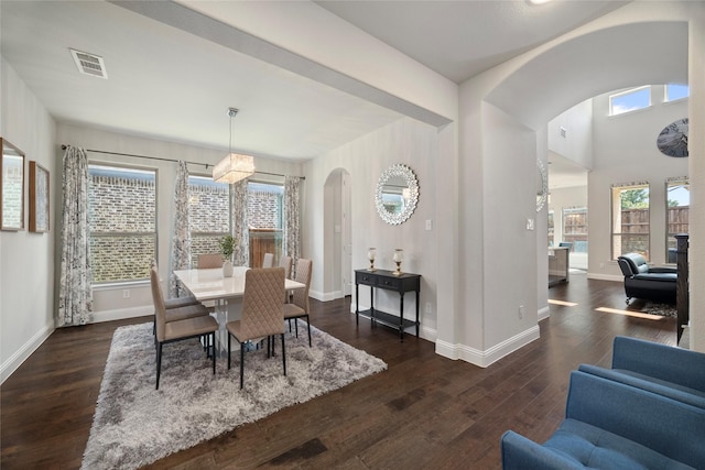 dining area with dark wood-style floors, visible vents, arched walkways, and baseboards