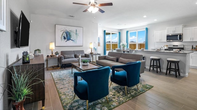 living room featuring light hardwood / wood-style floors and ceiling fan