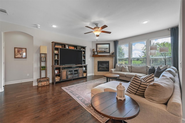 living room with ceiling fan, dark hardwood / wood-style flooring, and a tiled fireplace