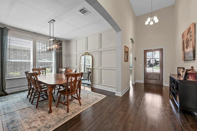 dining space featuring a notable chandelier, a high ceiling, and dark wood-type flooring