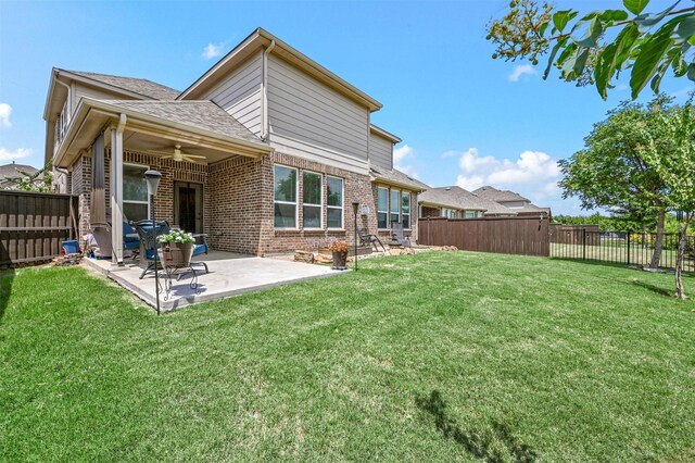 back of property with ceiling fan, a patio, and a lawn