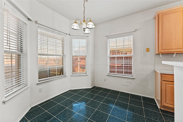 unfurnished dining area with a healthy amount of sunlight, a textured ceiling, and a notable chandelier