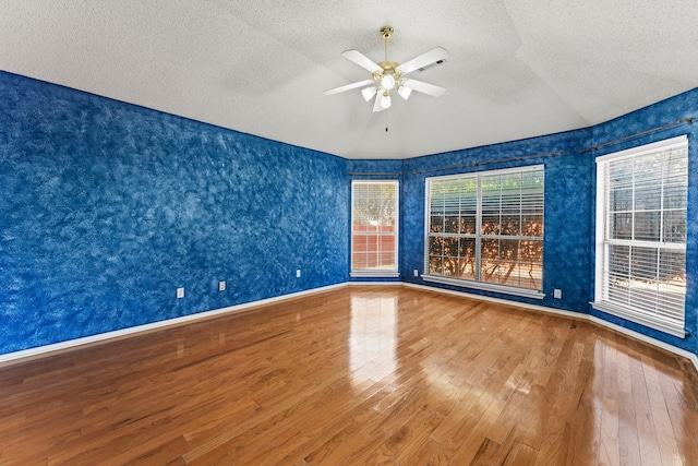 unfurnished room featuring ceiling fan, lofted ceiling, hardwood / wood-style floors, and a textured ceiling