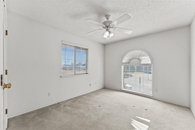 carpeted empty room with ceiling fan, a textured ceiling, and a wealth of natural light