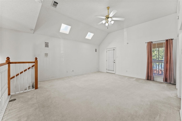 carpeted empty room with lofted ceiling with skylight and ceiling fan