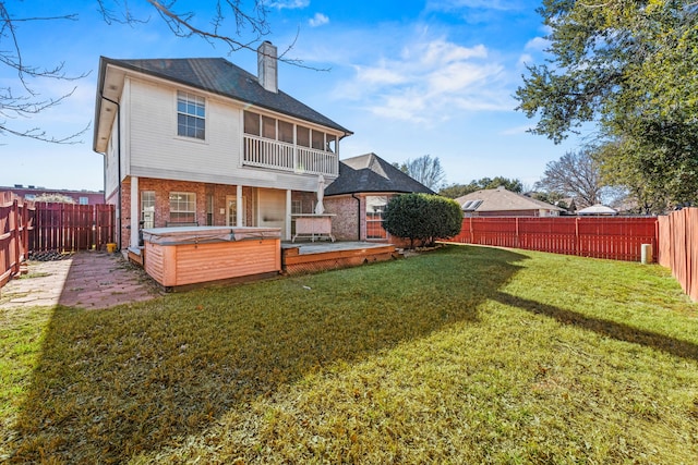 back of house with a patio, a hot tub, and a lawn