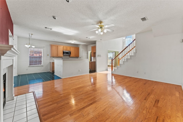 unfurnished living room with hardwood / wood-style floors and ceiling fan with notable chandelier