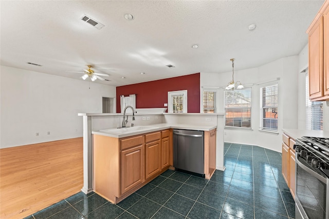 kitchen with sink, appliances with stainless steel finishes, a textured ceiling, light brown cabinetry, and decorative light fixtures