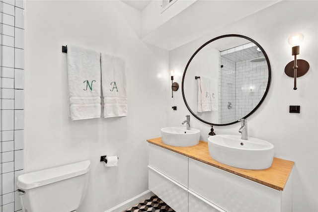 bathroom featuring tiled shower, toilet, and vanity