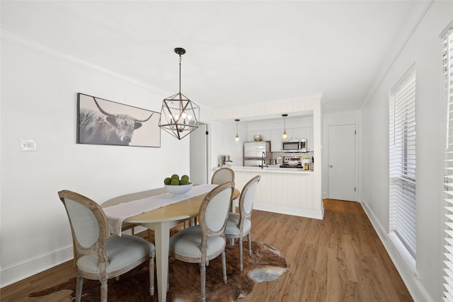 dining room with a chandelier, crown molding, and wood-type flooring