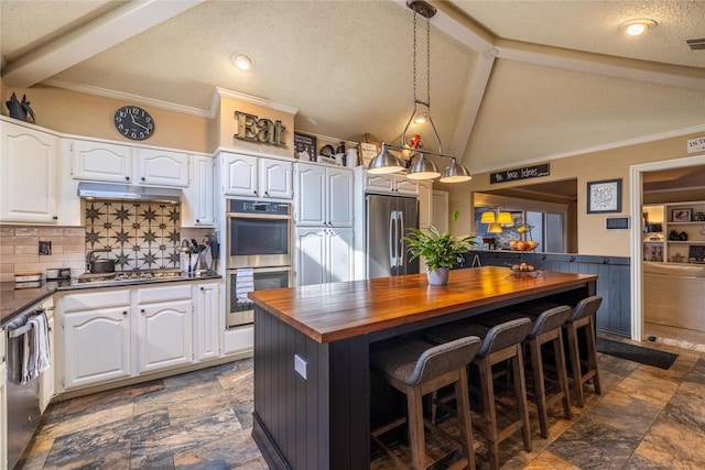 kitchen with appliances with stainless steel finishes, lofted ceiling with beams, white cabinets, wood counters, and decorative backsplash