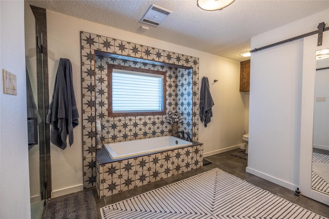 bathroom with a relaxing tiled tub, a textured ceiling, and toilet