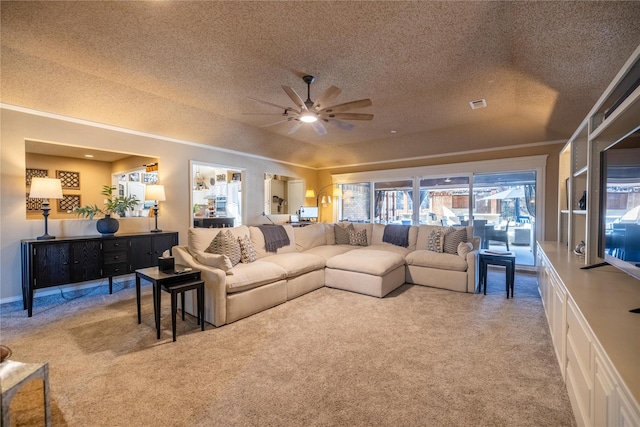 living room with a textured ceiling, ornamental molding, ceiling fan, and carpet flooring