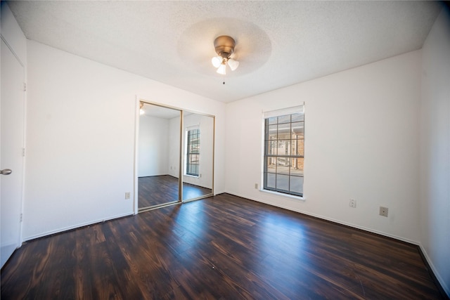 unfurnished bedroom featuring a closet, ceiling fan, dark hardwood / wood-style floors, and a textured ceiling