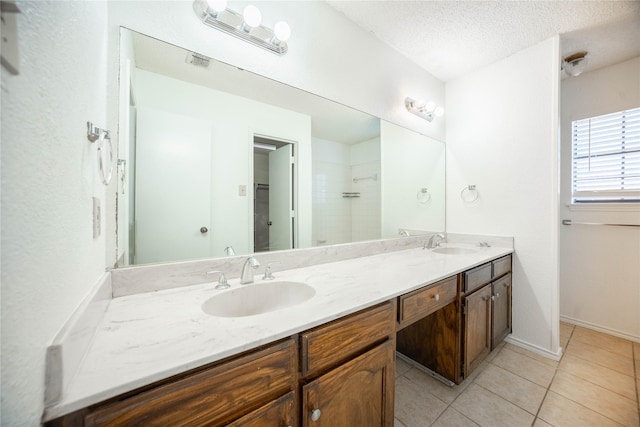 bathroom featuring vanity, tiled shower, a textured ceiling, and tile patterned flooring