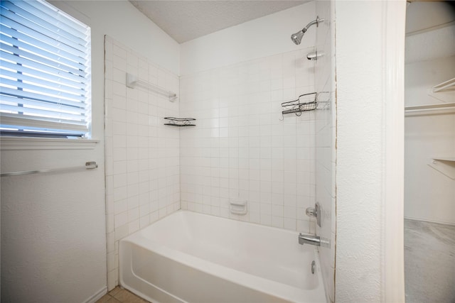 bathroom with tile patterned floors, tiled shower / bath, and a textured ceiling