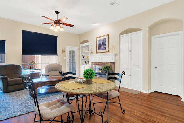 9435 Homestead Ln, Frisco, TX 75033 - dining room featuring built in shelves, a glass covered fireplace, ceiling fan, wood finished floors, and baseboards