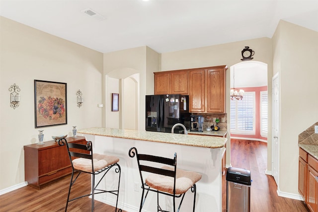 9435 Homestead Ln, Frisco, TX 75033 - kitchen with black refrigerator with ice dispenser, arched walkways, light wood-style floors, and a breakfast bar area