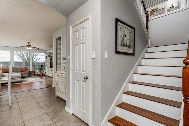 stairway with ceiling fan and tile patterned floors