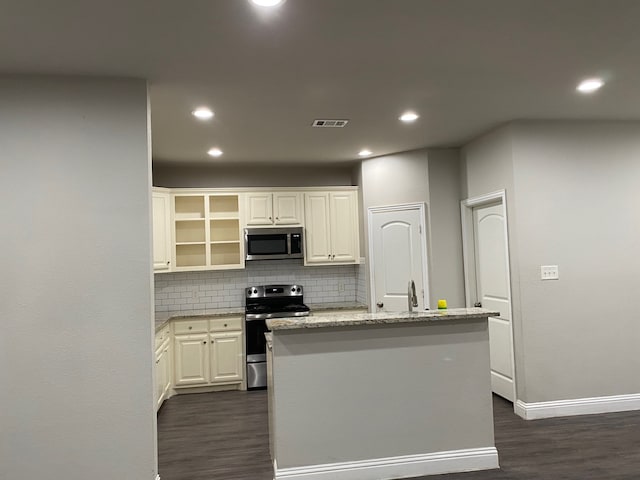 kitchen featuring tasteful backsplash, a kitchen island with sink, white cabinets, and appliances with stainless steel finishes