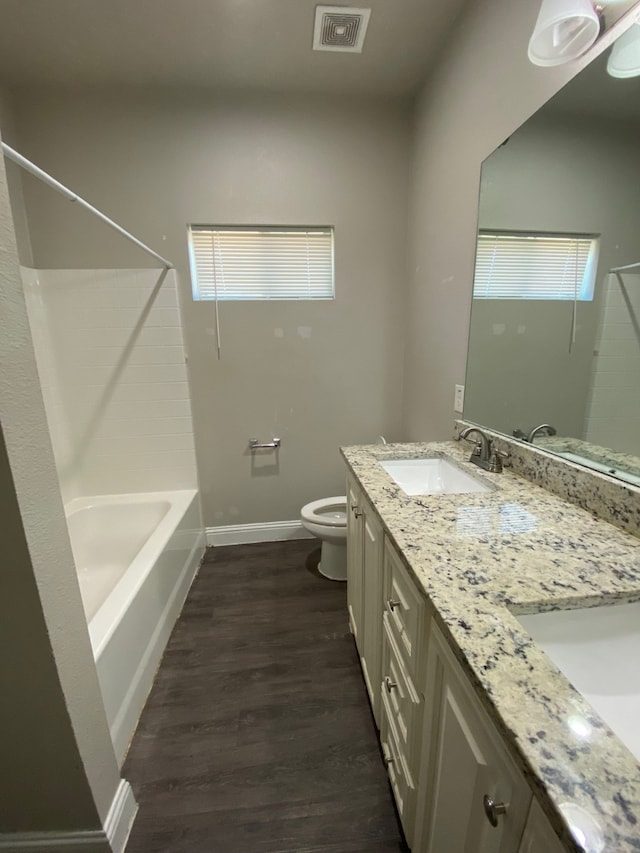 full bathroom featuring wood-type flooring, vanity, a healthy amount of sunlight, shower / washtub combination, and toilet