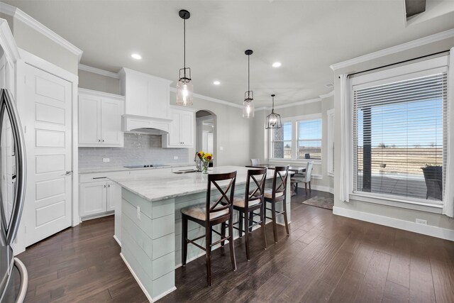 kitchen with a kitchen bar, pendant lighting, and white cabinetry