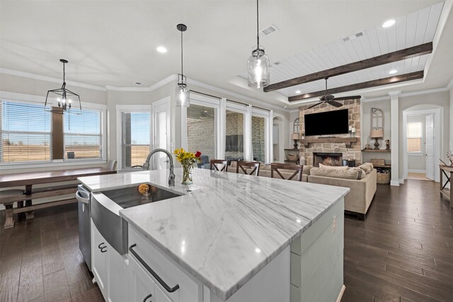 kitchen featuring pendant lighting, white cabinets, appliances with stainless steel finishes, a large island with sink, and dark wood-type flooring