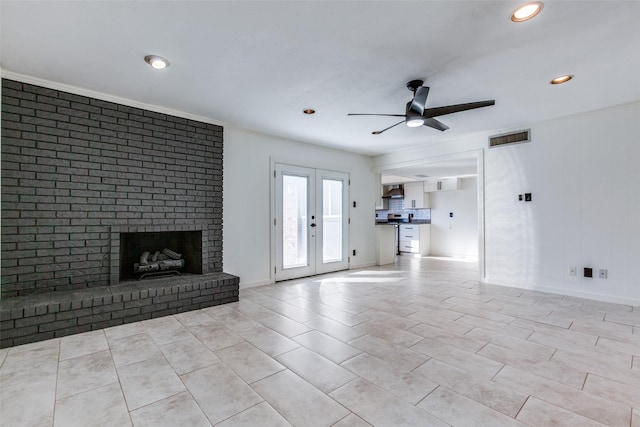 unfurnished living room featuring crown molding, a brick fireplace, light tile patterned floors, french doors, and ceiling fan