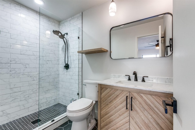 bathroom featuring toilet, a tile shower, tile patterned floors, vanity, and ceiling fan