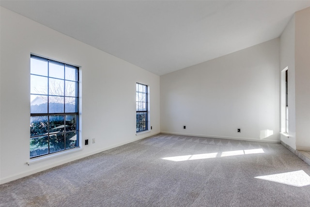 spare room with light colored carpet and lofted ceiling