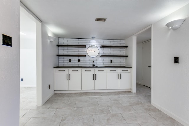 kitchen with white cabinets, light tile patterned flooring, decorative backsplash, and sink