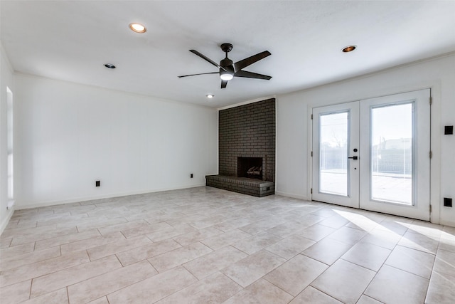 unfurnished living room with french doors, ceiling fan, light tile patterned flooring, a brick fireplace, and crown molding