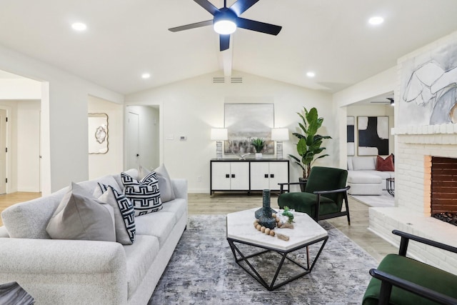 living room with a fireplace, hardwood / wood-style flooring, ceiling fan, and lofted ceiling