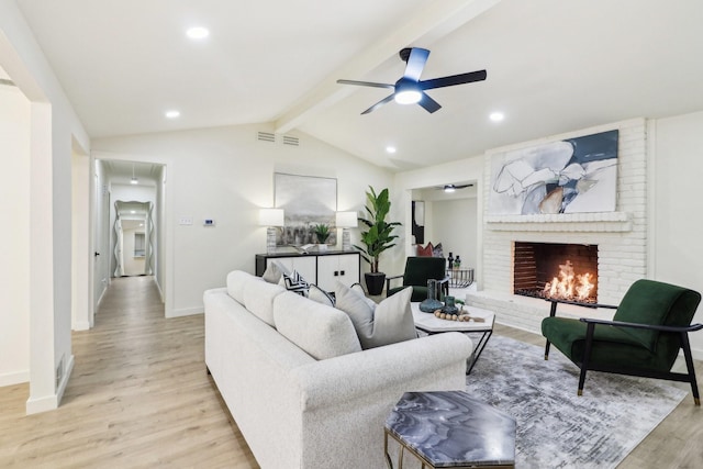 living room with ceiling fan, light wood-type flooring, vaulted ceiling with beams, and a brick fireplace