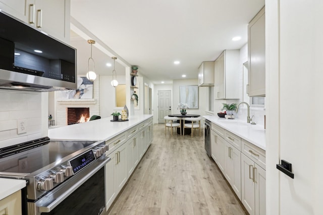 kitchen featuring hanging light fixtures, light wood-type flooring, white cabinetry, decorative backsplash, and stainless steel appliances