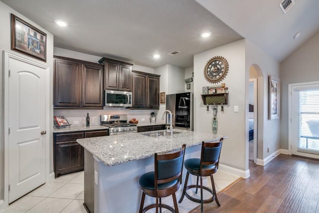 kitchen with a kitchen island with sink, sink, a kitchen breakfast bar, and appliances with stainless steel finishes