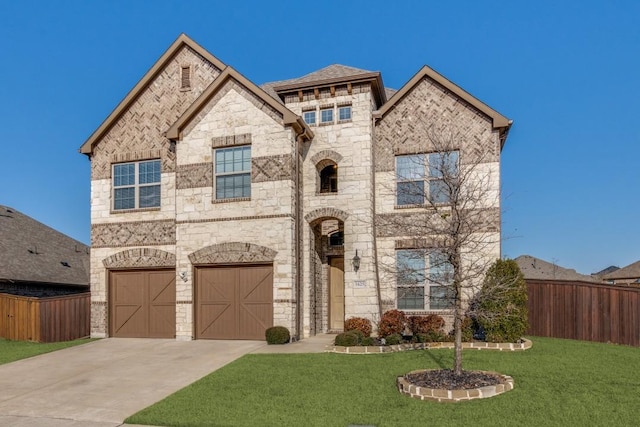 french country home with a front yard, fence, concrete driveway, a garage, and stone siding