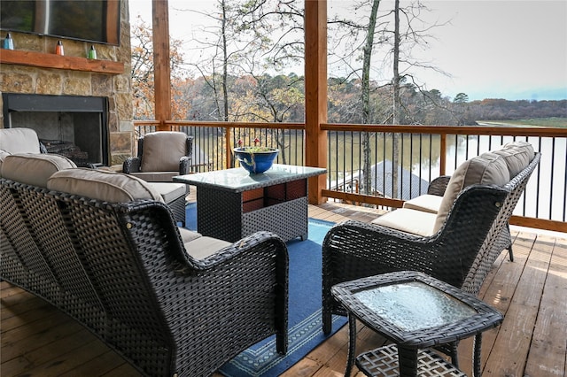 wooden terrace featuring a water view and an outdoor stone fireplace