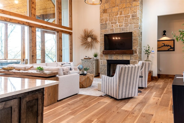 living room featuring light hardwood / wood-style flooring, a towering ceiling, and a fireplace