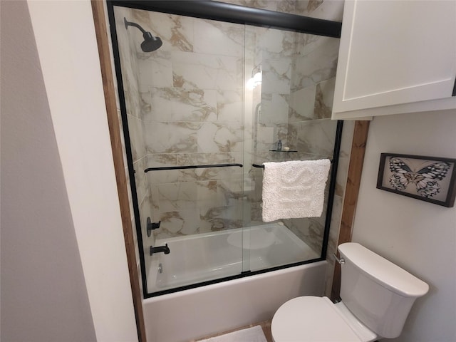 bathroom featuring toilet and bath / shower combo with glass door