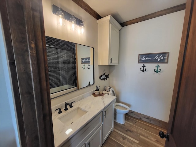 bathroom with toilet, hardwood / wood-style floors, walk in shower, ornamental molding, and vanity