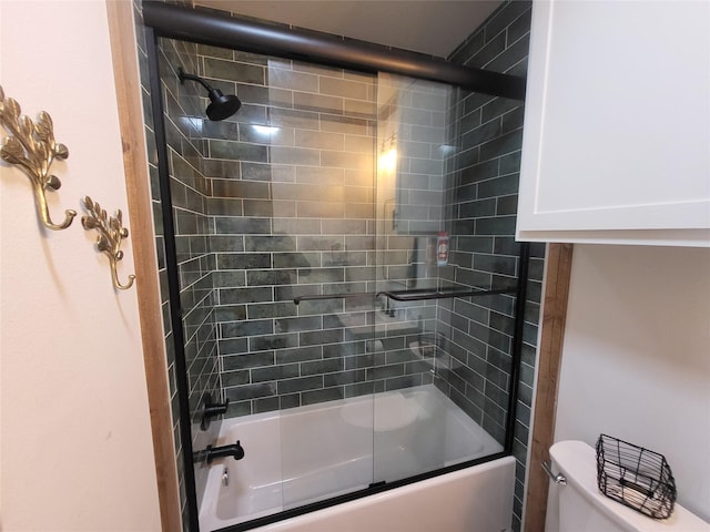 bathroom featuring combined bath / shower with glass door and toilet